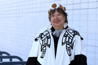 Chancellor Judith Sayers smiling, wearing traditional Indigenous clothing outdoors