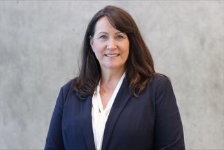 Corry Gervais smiling, wearing a navy blue suit in an airy modern room